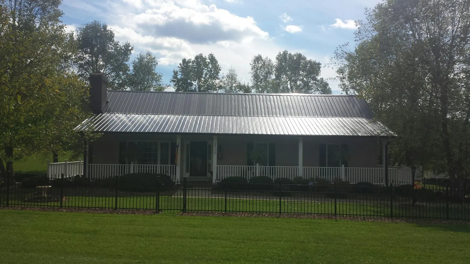 Gray metal roof on a brick ranch with a full width front porch — Gutter Guard Installation work by our crew in Greenfield